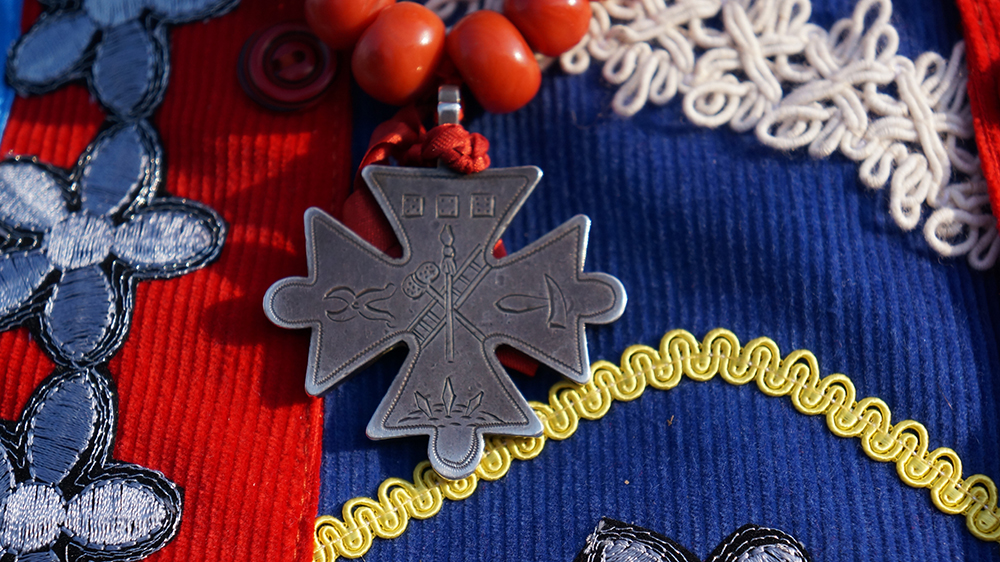 Zgodnie z tradycją, równoramienny, srebrny krzyż wilamowski przypinany jest do korali.